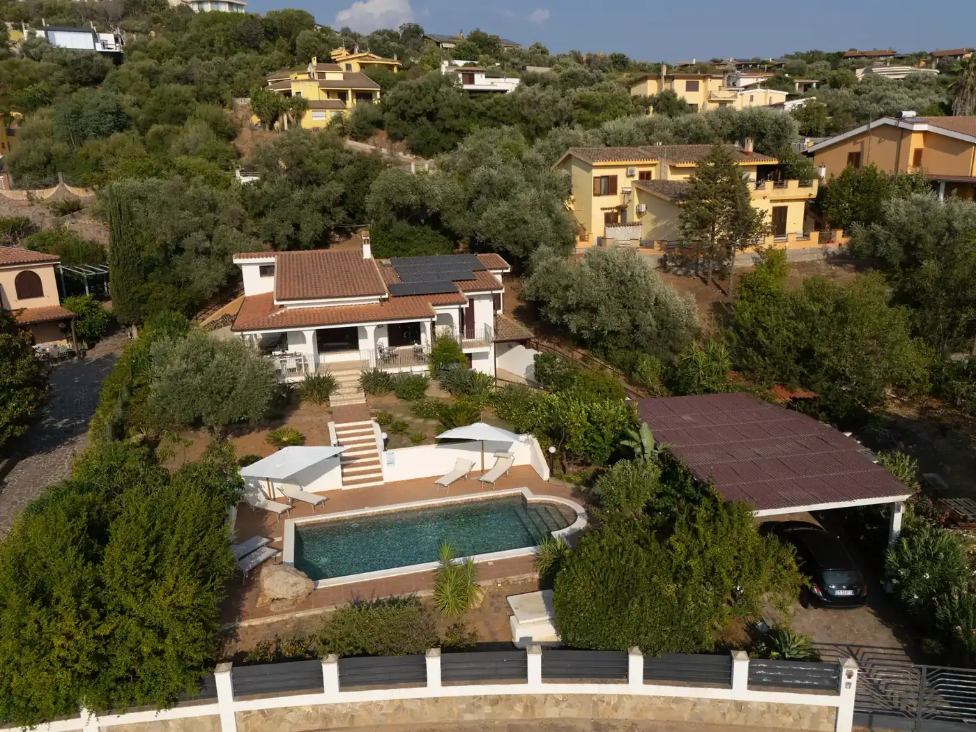 Niu Crobu von oben: grüner Hügel mit Häusern und dem Pool der Villa