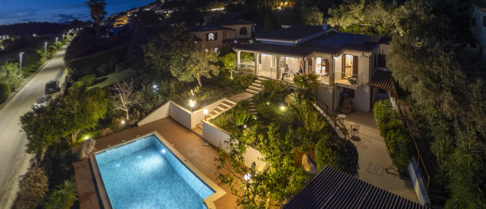 La villa di sera, con la piscina e il giardino illuminati