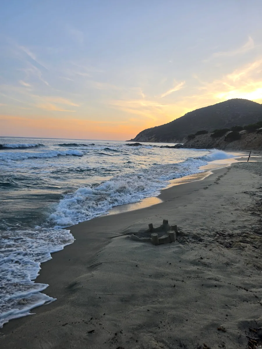 Strand bei Sonnenuntergang mit einer Sandburg